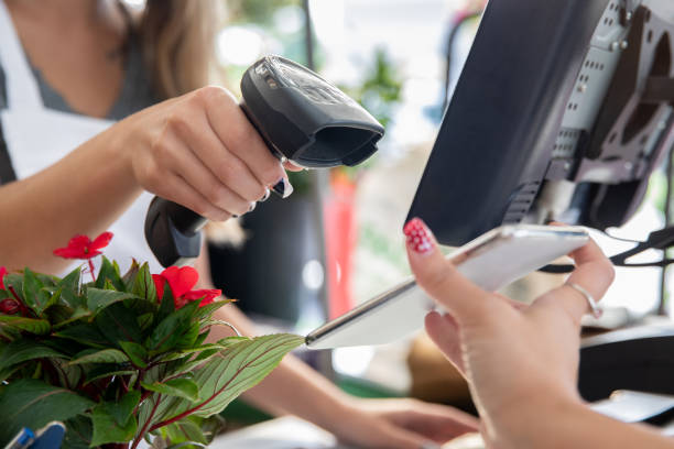 Employee scans smart phone to take payment at garden center or plant nursery Employee scans smart phone to take payment at garden center or plant nursery